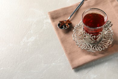 Glass of traditional Turkish tea in vintage holder and anise star on white marble table. Space for text