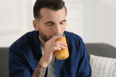 Photo of Handsome man drinking delicious smoothie at home
