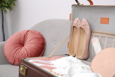 Vintage suitcase with clothes and shoes on sofa indoors