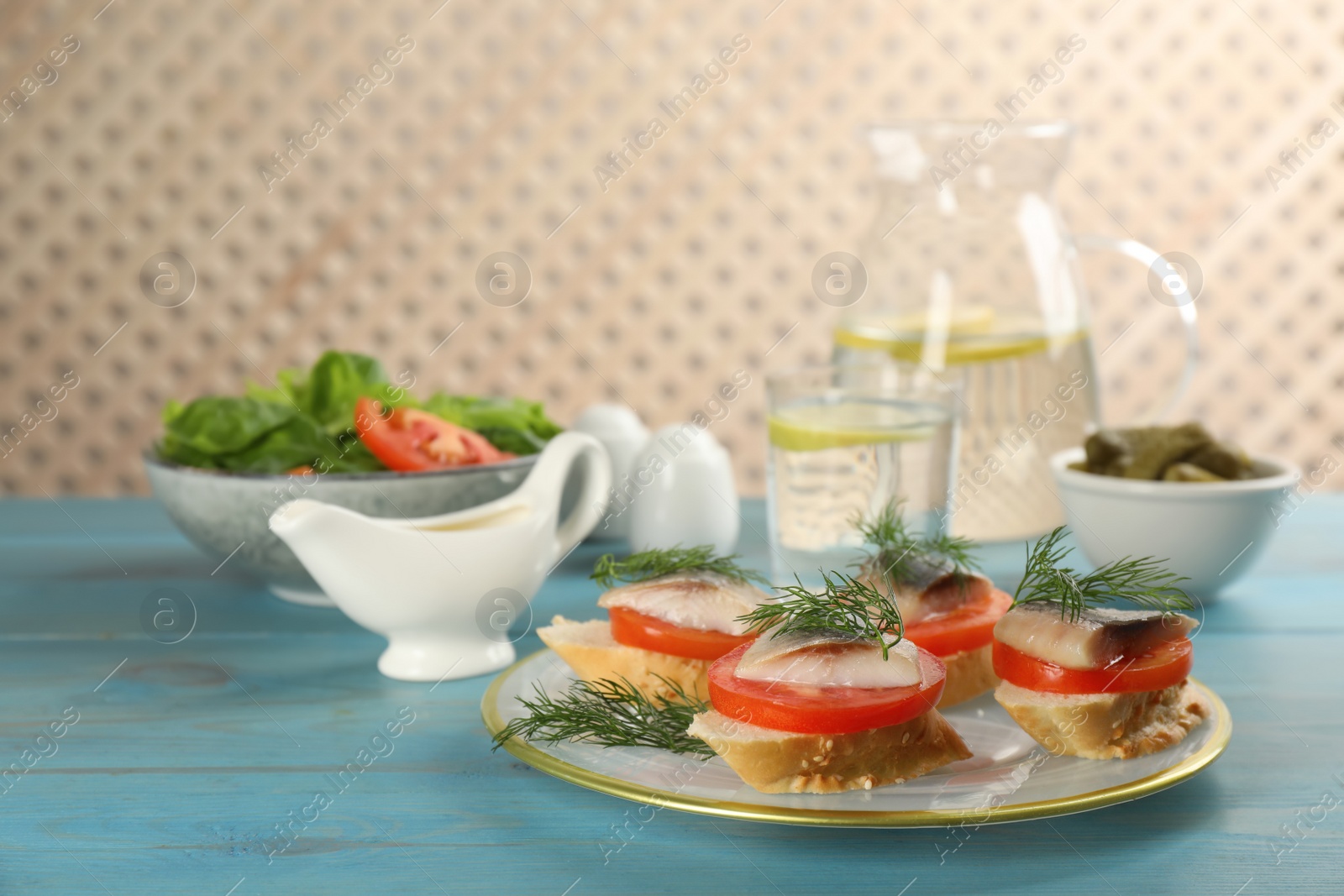 Photo of Delicious sandwiches with salted herring, tomatoes and dill on light blue wooden table
