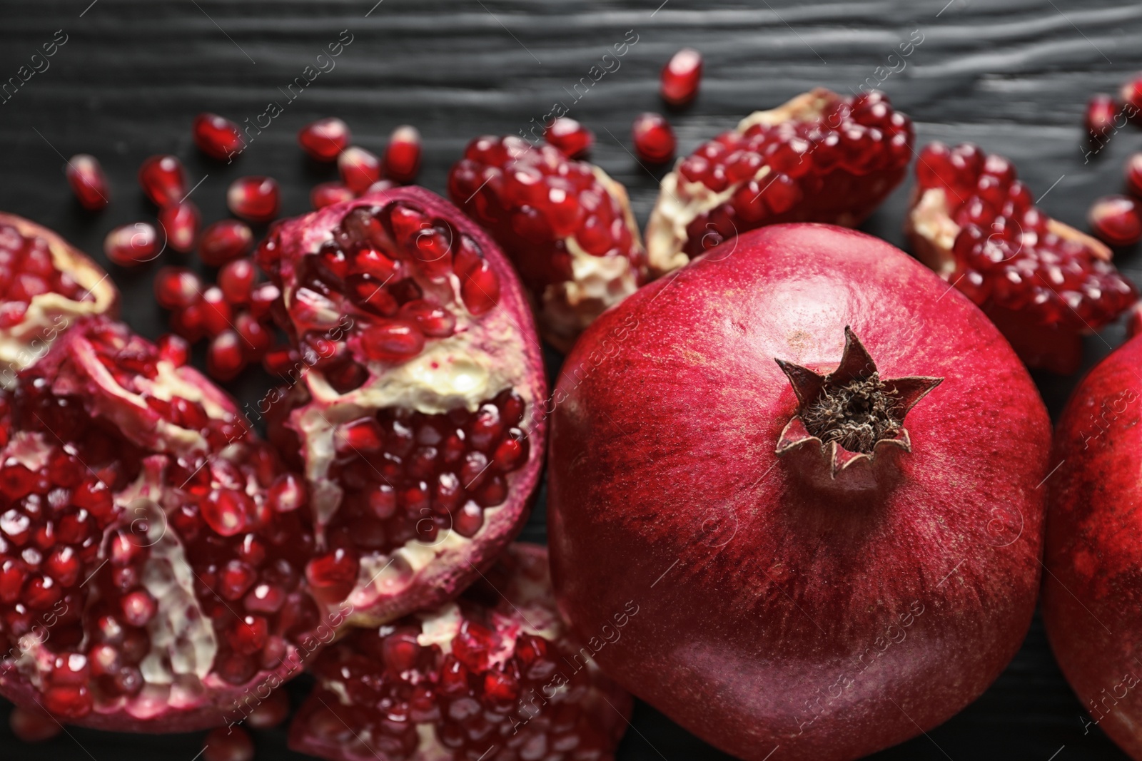 Photo of Ripe pomegranates on dark wooden background, top view