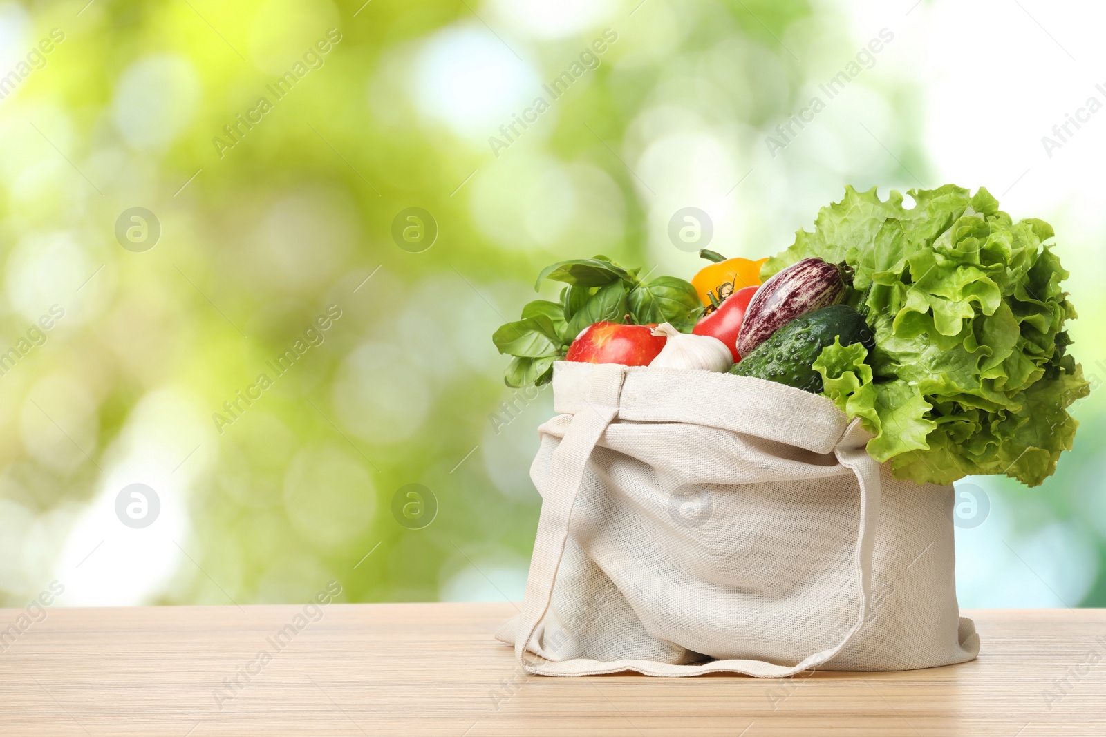 Image of Fresh vegetables in cloth bag on wooden table against blurred background. Space for text