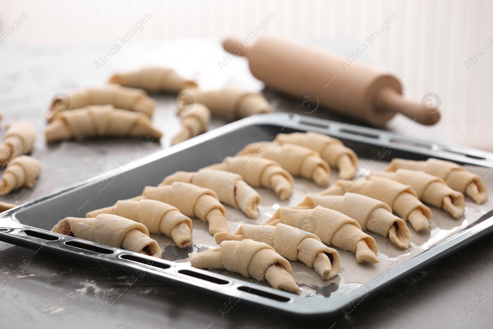 Photo of Baking sheet with raw croissants on table