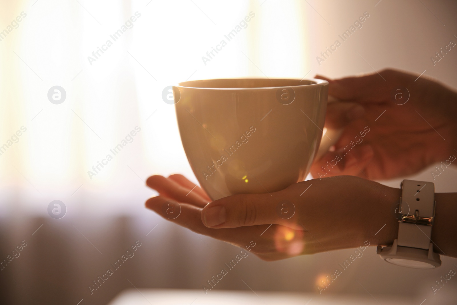 Photo of Woman holding cup of drink on blurred background, closeup. Lazy morning