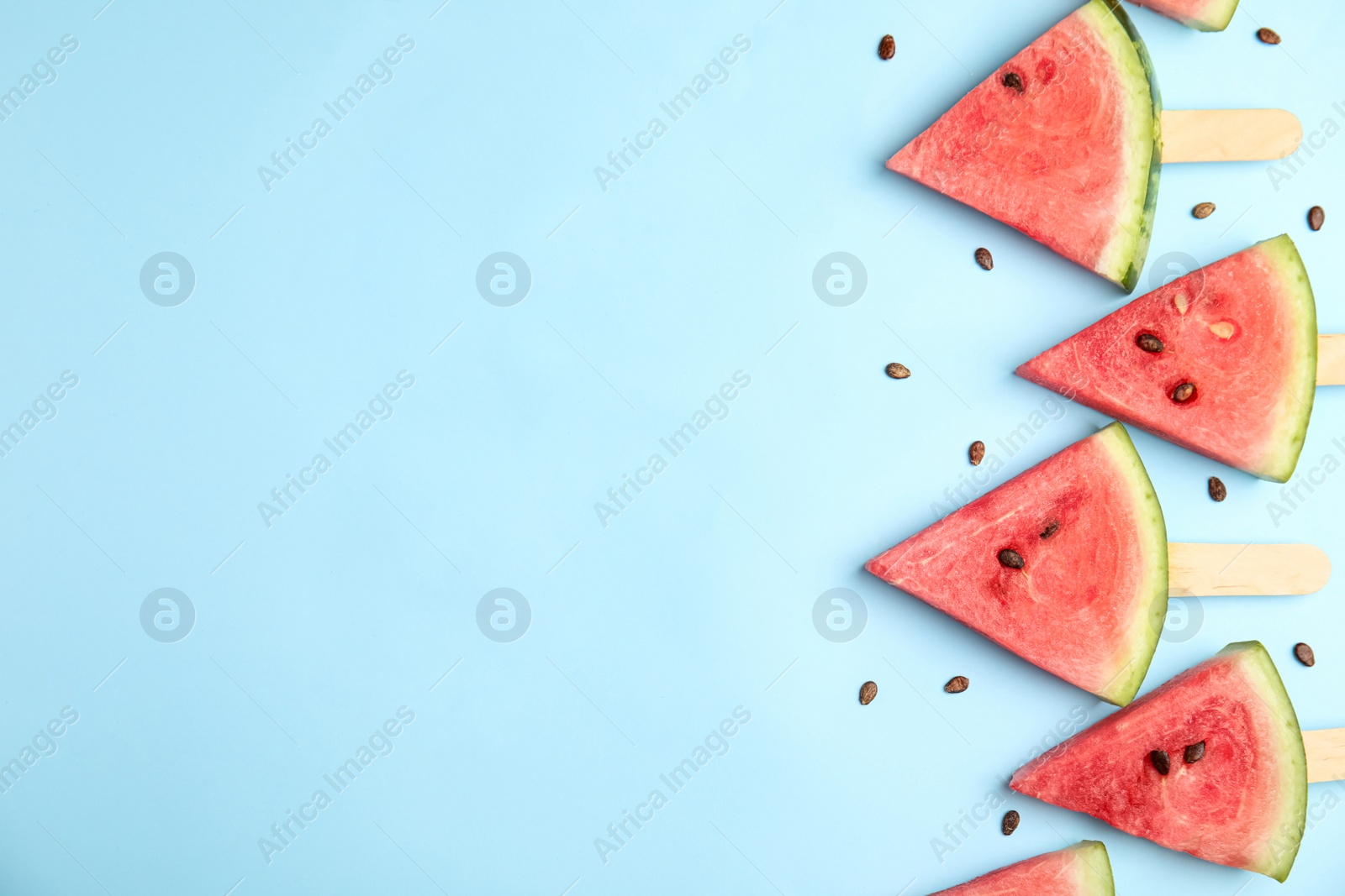 Photo of Slices of ripe watermelon on light blue background, flat lay. Space for text