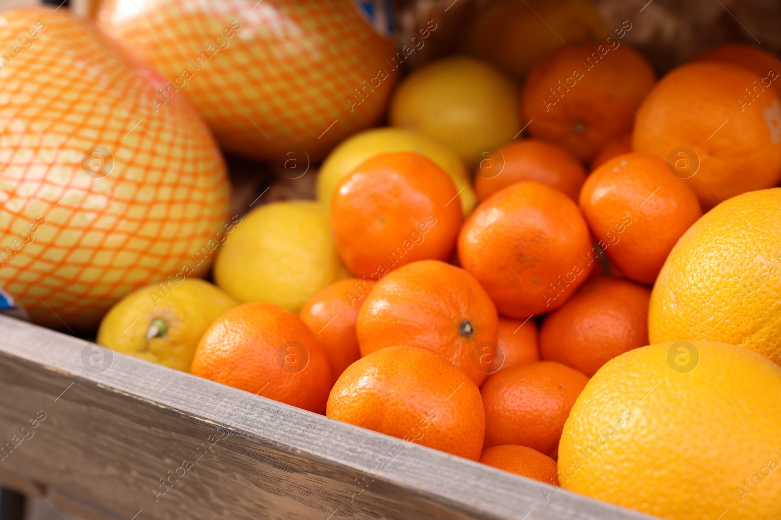 Photo of Fresh ripe fruits in wooden crate at market, selective focus