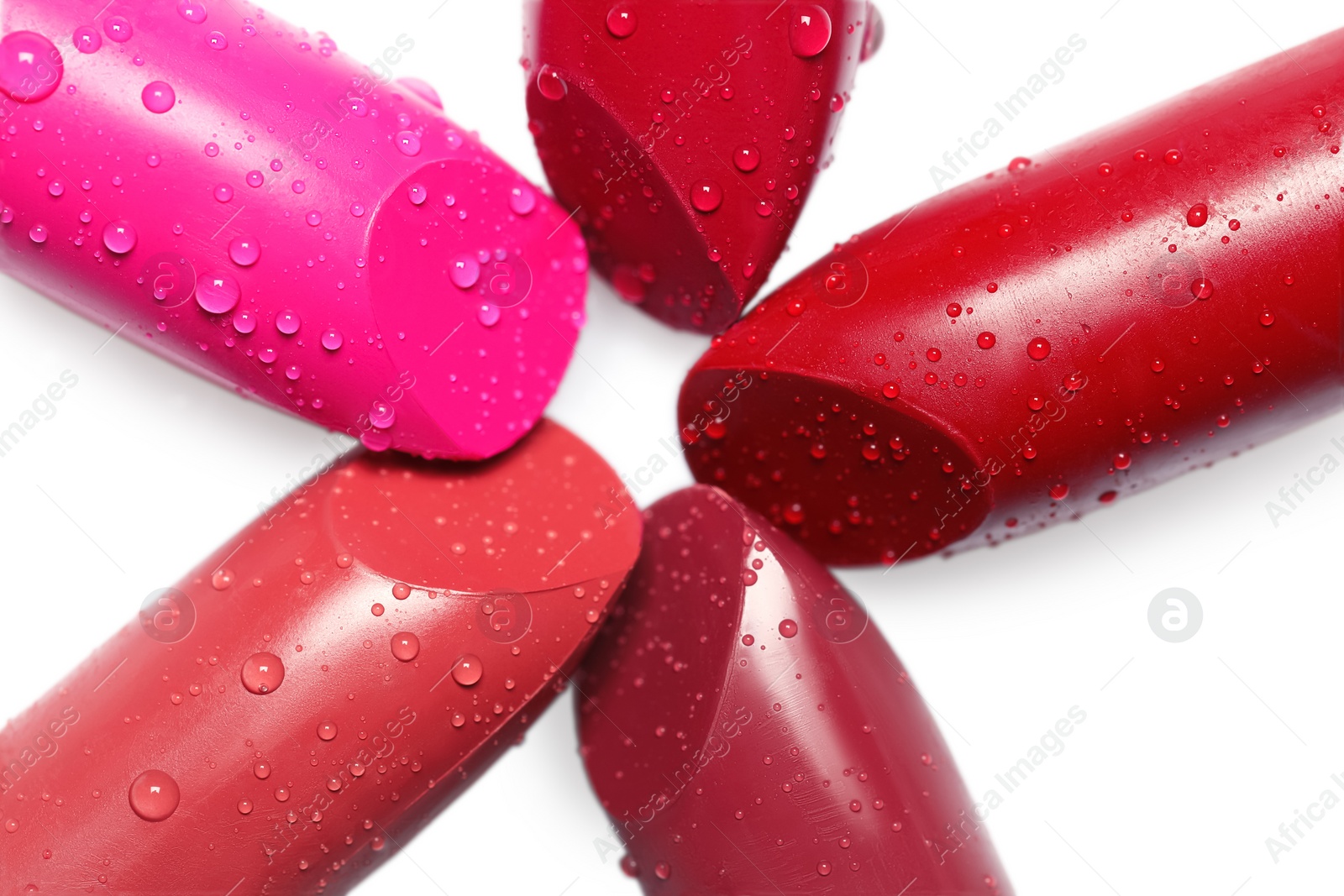 Photo of Many bright lipsticks with water drops on white background, top view