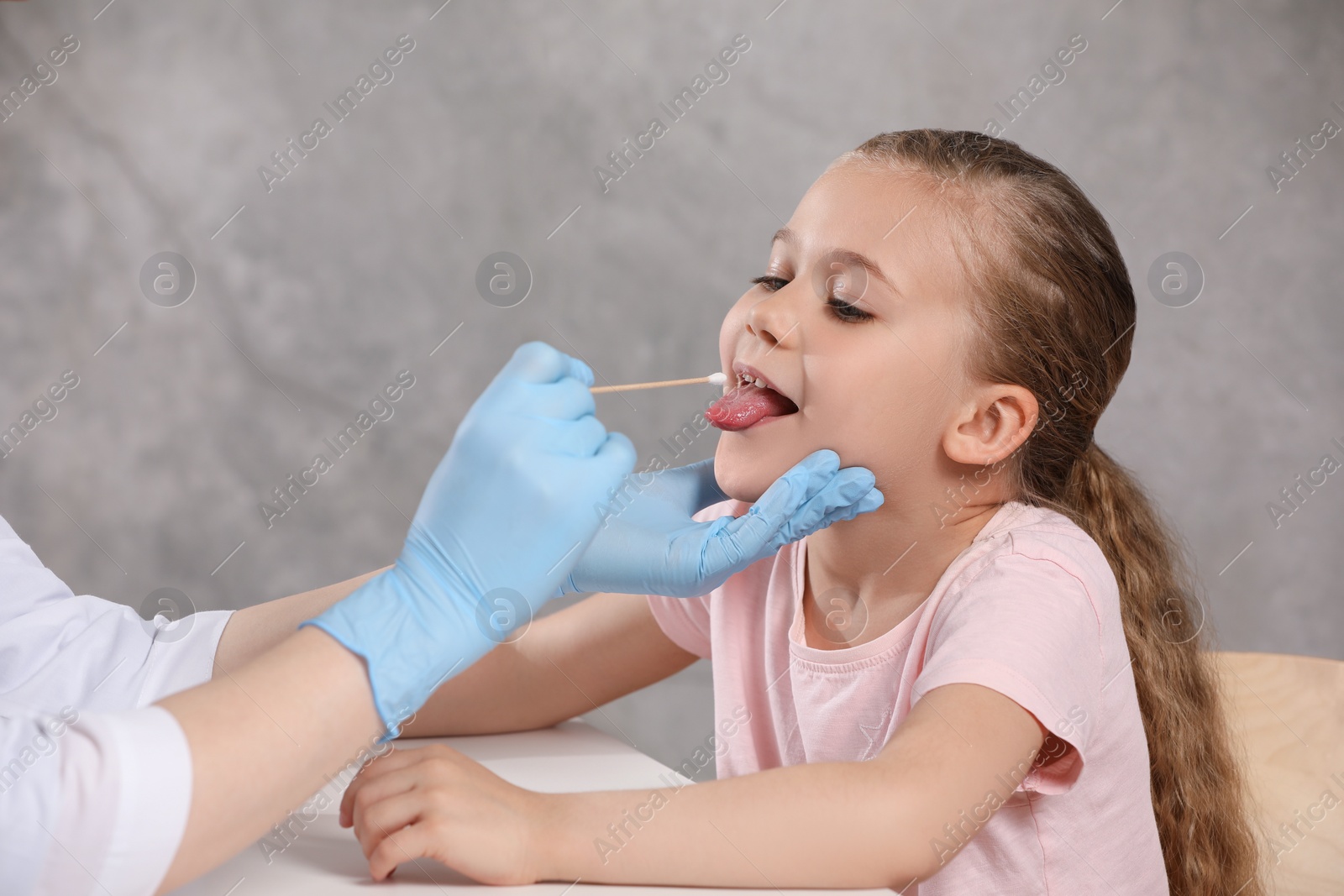Photo of Doctor taking throat swab sample from girl`s oral cavity indoors, closeup
