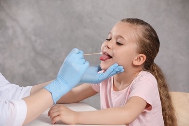 Photo of Doctor taking throat swab sample from girl`s oral cavity indoors, closeup