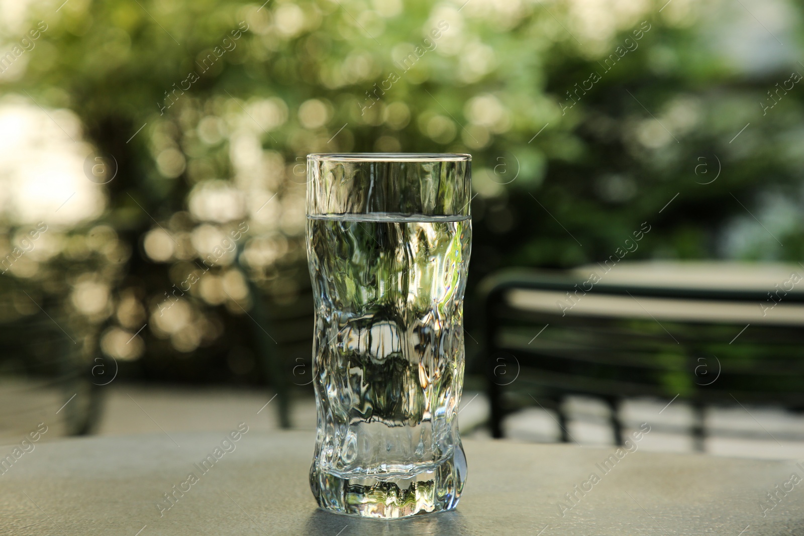 Photo of Glass of fresh water on grey table outdoors