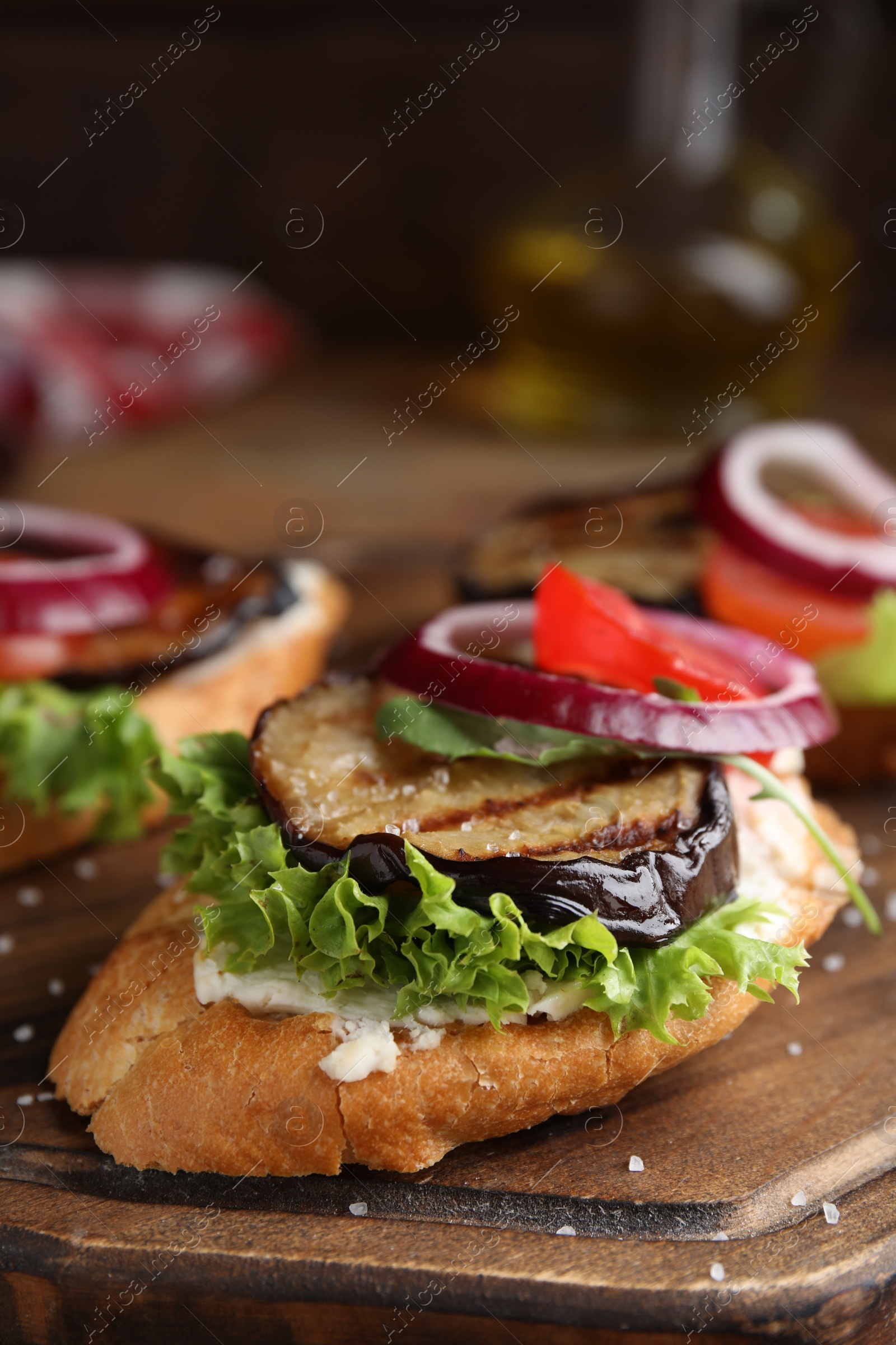 Photo of Delicious eggplant sandwiches served on wooden board, closeup