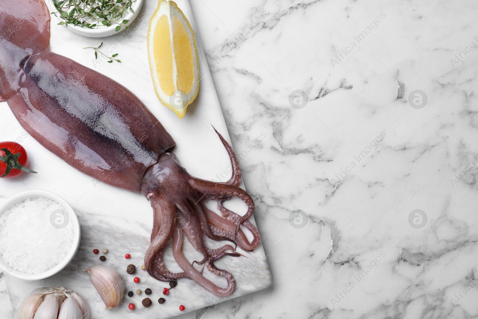 Photo of Fresh raw squid served on white marble table, top view. Space for text