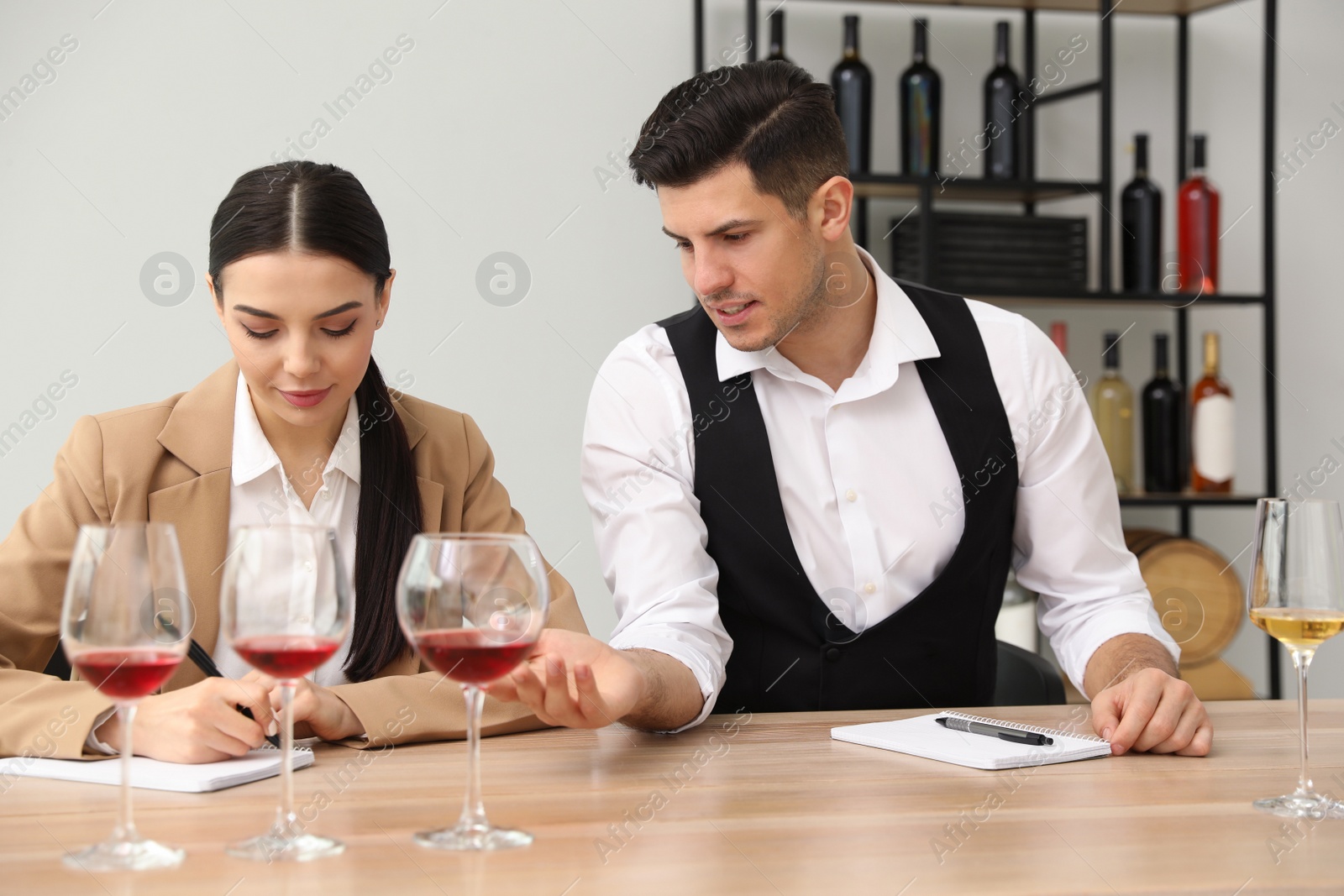 Photo of Sommeliers tasting different sorts of wine at table indoors