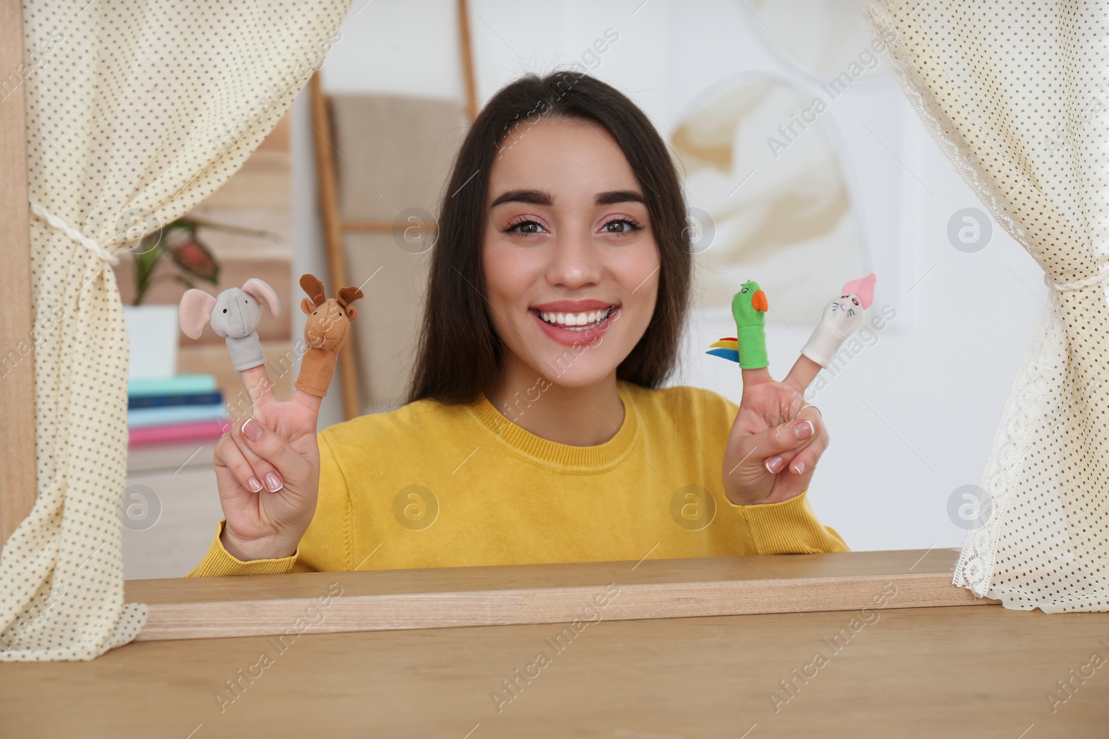 Photo of Young woman performing puppet show at home