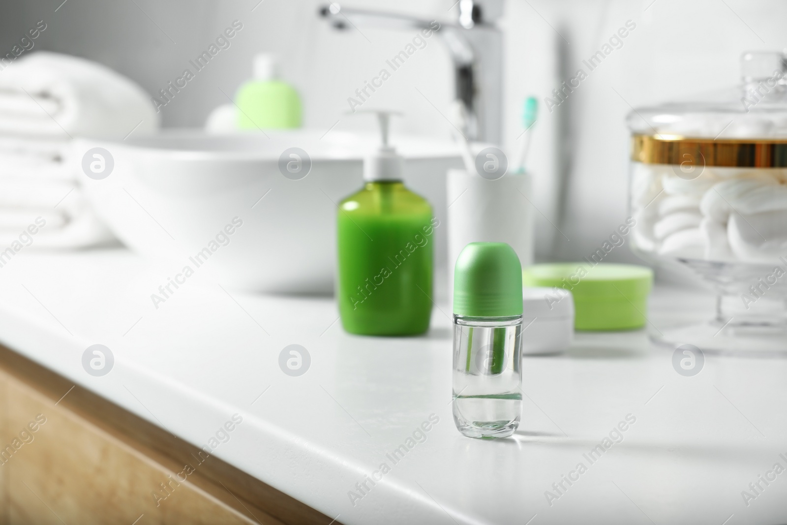 Photo of Roll-on deodorant and toiletry on countertop in bathroom, space for text