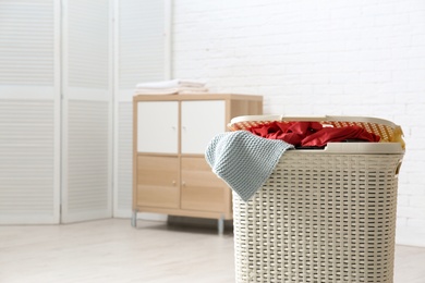 Photo of Laundry basket with dirty clothes indoors. Space for text