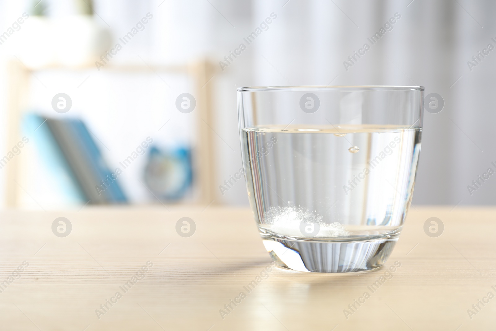 Photo of Glass of water with effervescent tablet on wooden table indoors, space for text