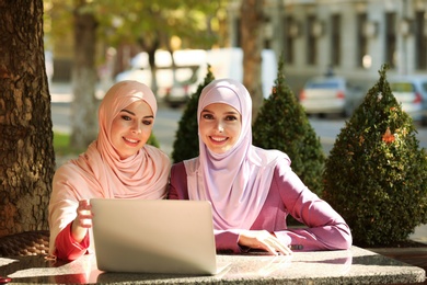 Photo of Muslim women with laptop sitting in outdoor cafe