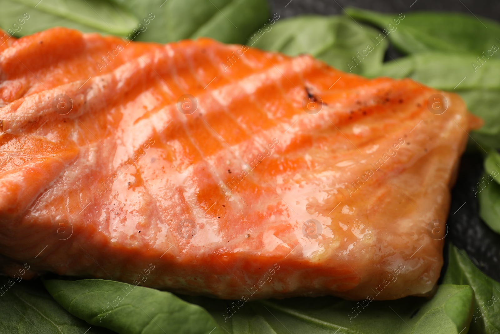 Photo of Tasty grilled salmon with spinach on table, closeup