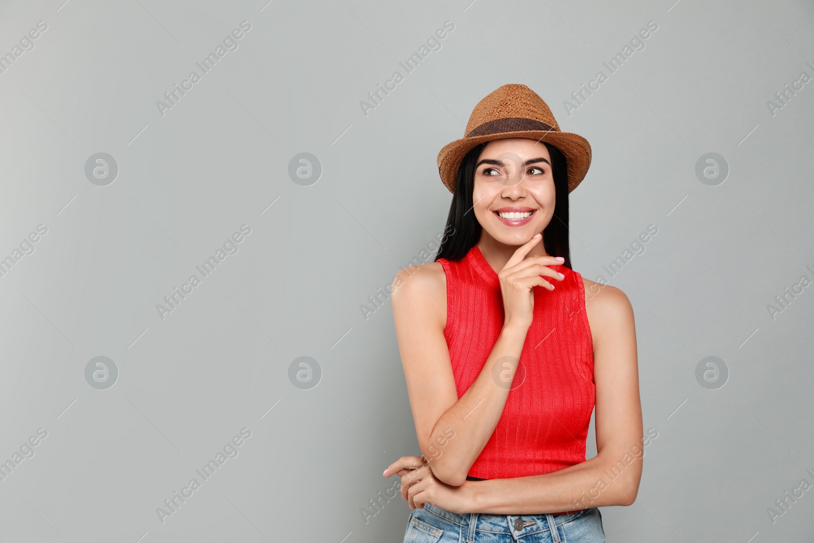 Photo of Beautiful young woman with straw hat on light grey background. Space for text