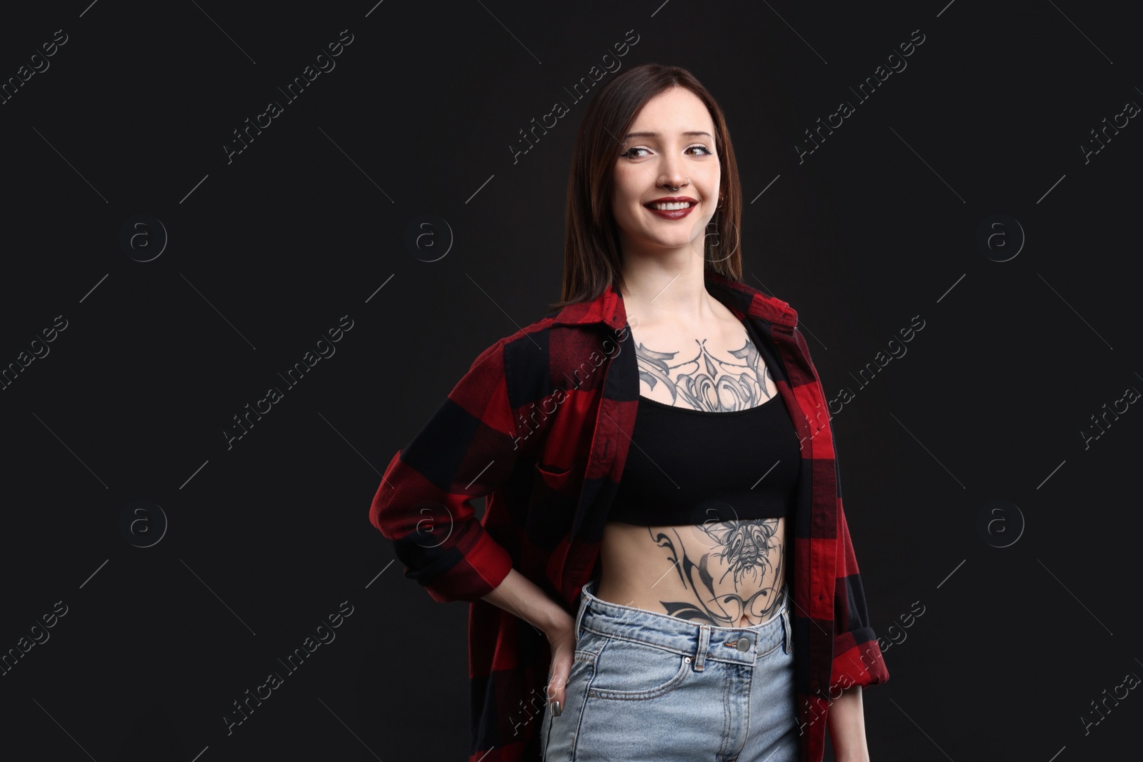 Photo of Portrait of smiling tattooed woman on black background. Space for text