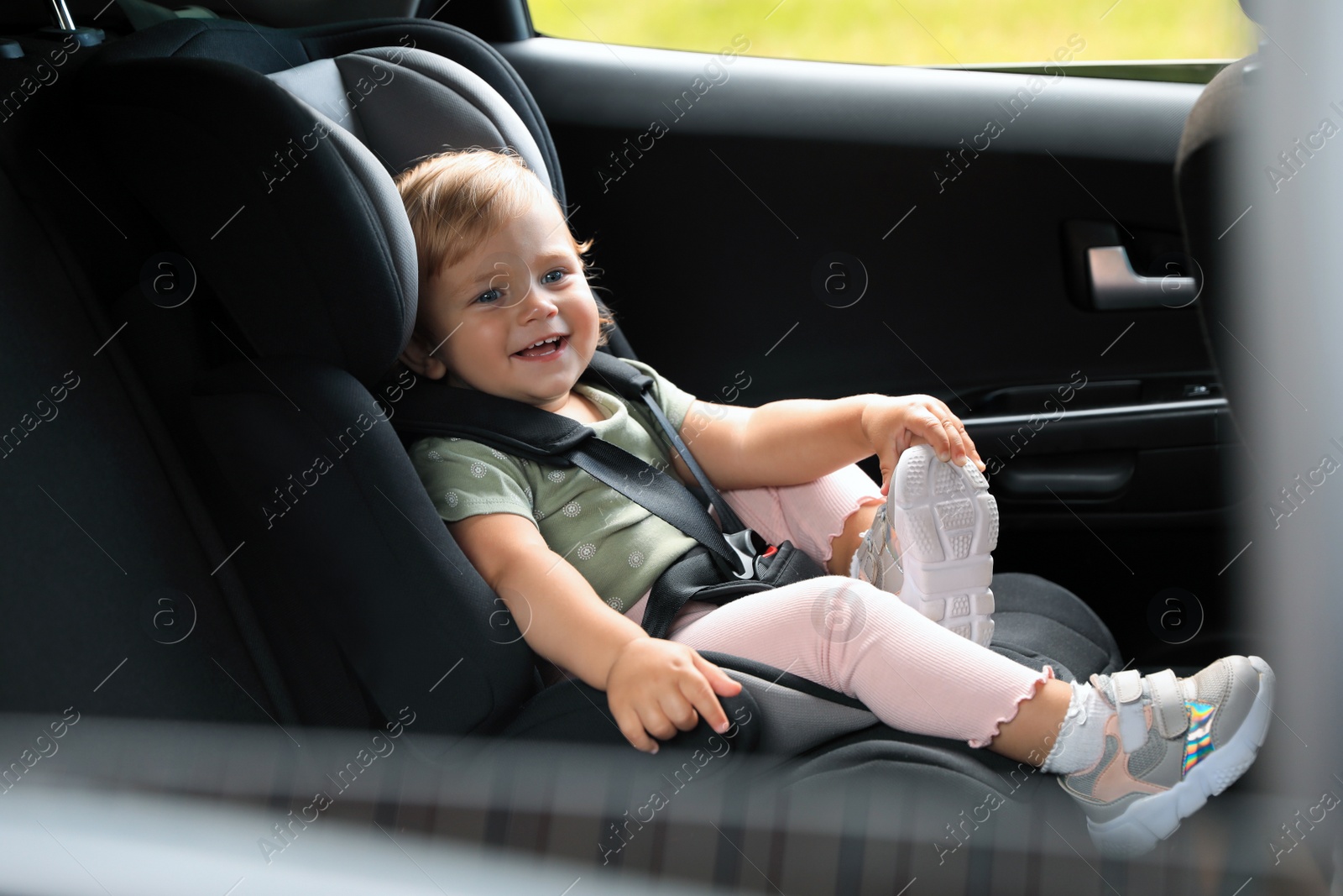 Photo of Cute little girl sitting in child safety seat inside car