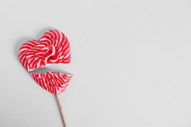 Broken heart shaped lollipop on white background, top view. Space for text