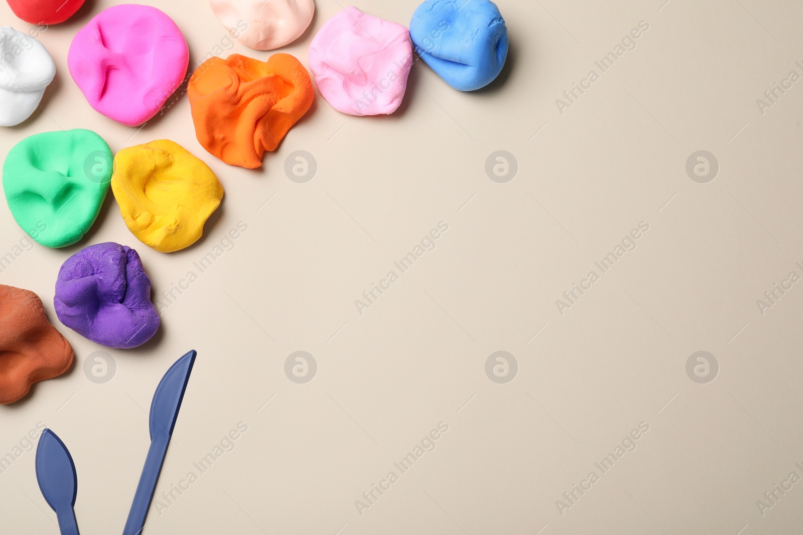 Photo of Colorful plasticine and tools on beige background, flat lay. Space for text