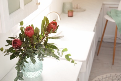 Bouquet with beautiful protea flowers on countertop in kitchen, space for text. Interior design