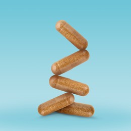 Image of Vitamin. Capsules falling on light blue gradient background