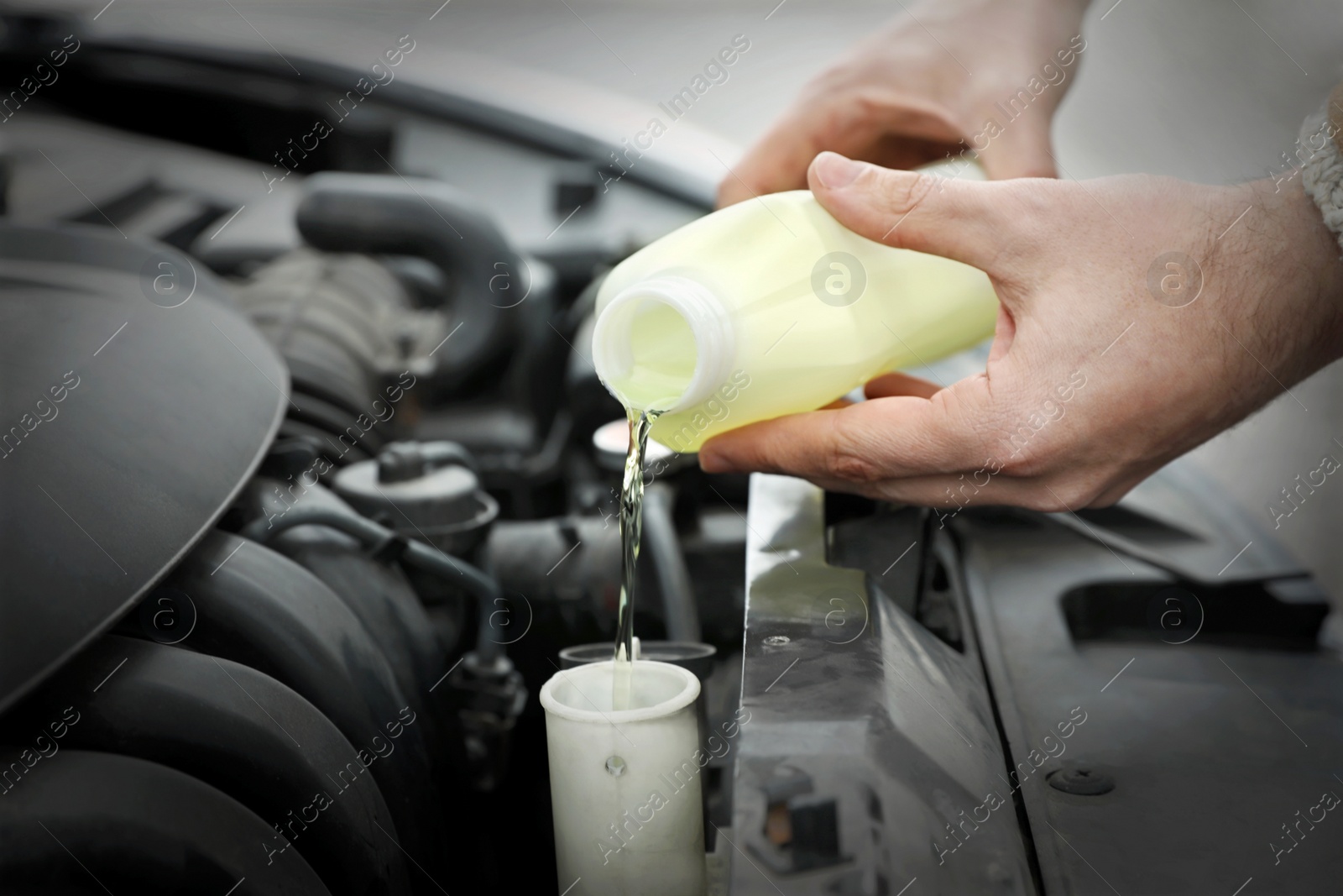 Photo of Man filling car radiator with antifreeze outdoors, closeup