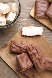Photo of Tasty chocolate bars and nougat on wooden table, flat lay
