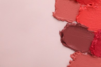 Smears of different beautiful lipsticks on light background, top view. Space for text