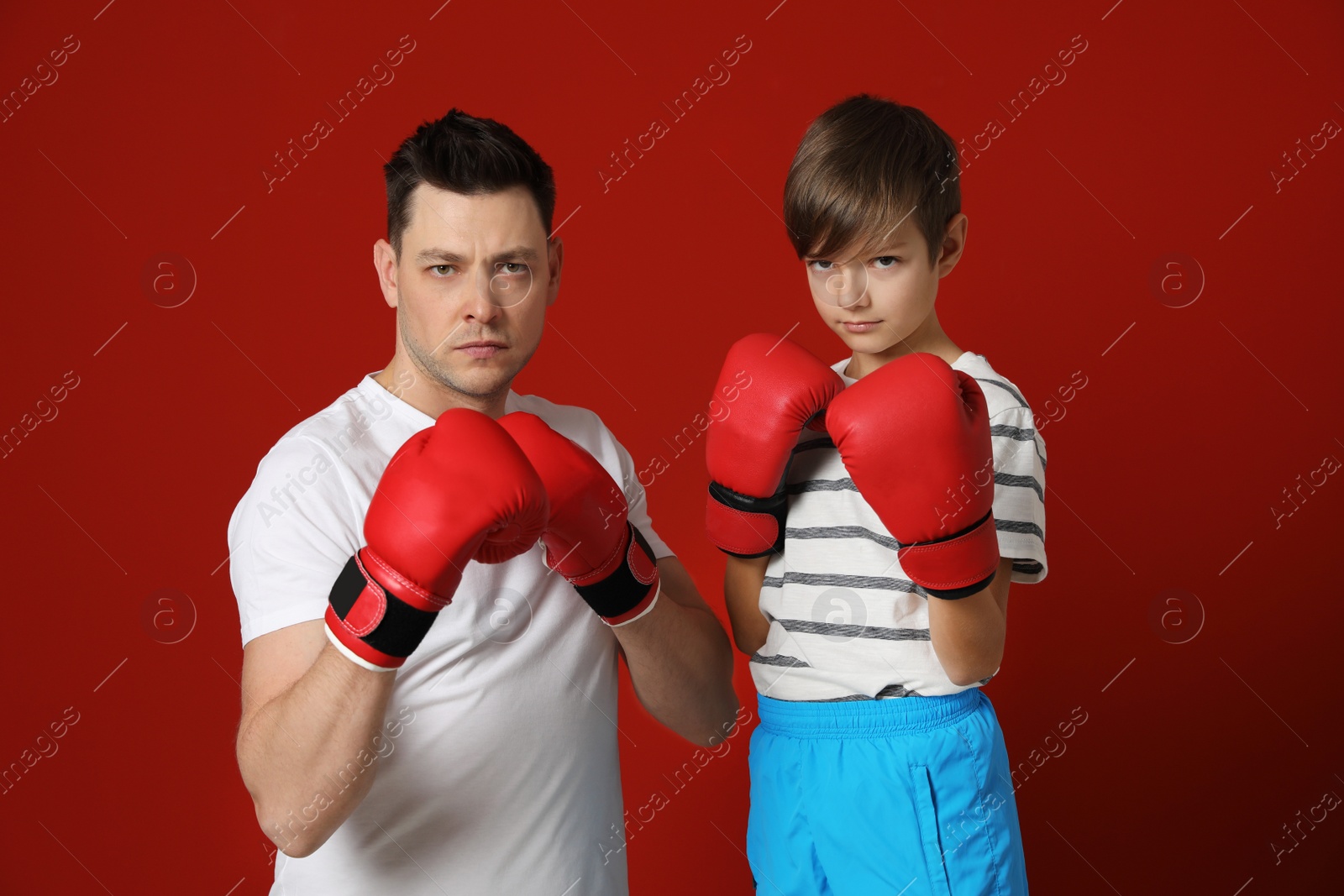 Photo of Dad and his son with boxing gloves on color background