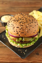 Photo of Burger with delicious patty, french fries and sauce on wooden table, closeup
