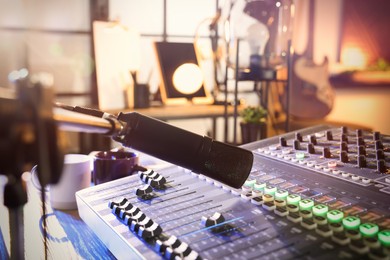 Photo of Microphone over professional mixing console on table in radio studio