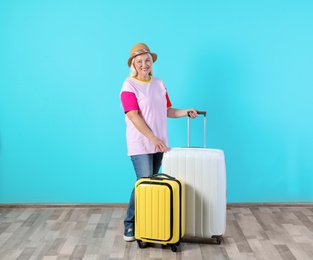 Photo of Senior woman with suitcases near color wall. Vacation travel