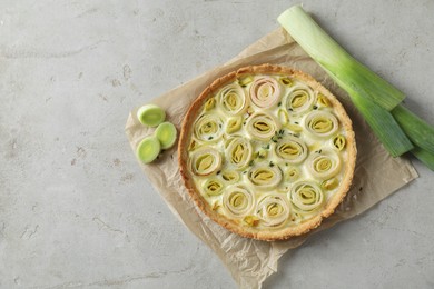 Tasty leek pie and fresh stalk on grey textured table, flat lay. Space for text