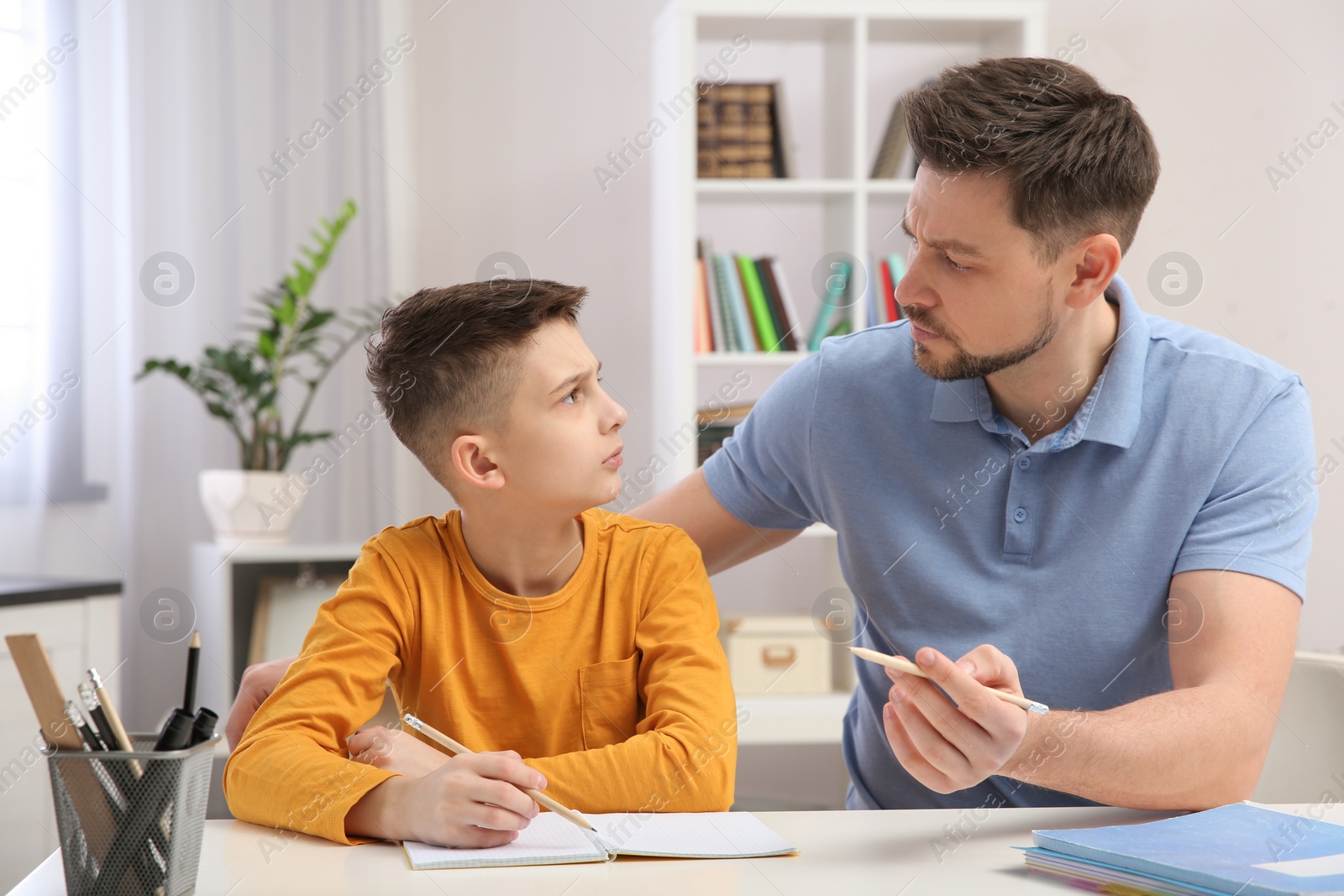 Photo of Dad helping his son with homework in room