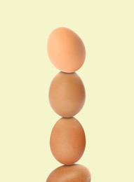 Stacked fresh chicken eggs against light beige background