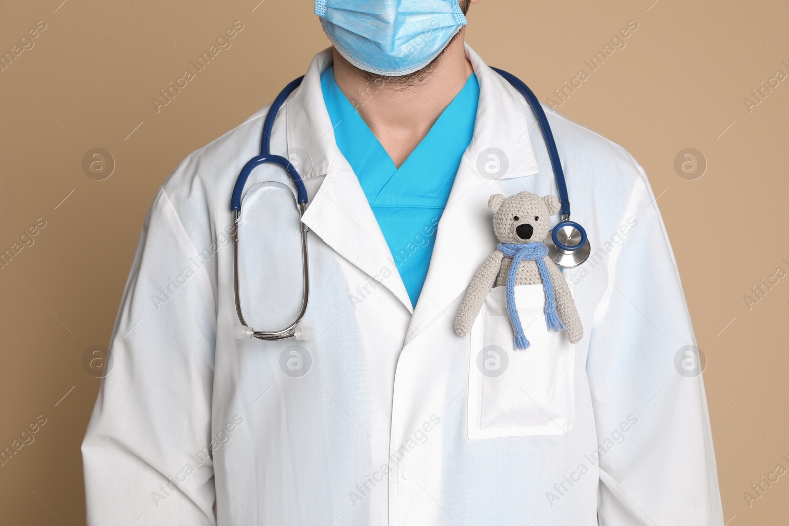 Photo of Pediatrician with toy bear and stethoscope on beige background, closeup