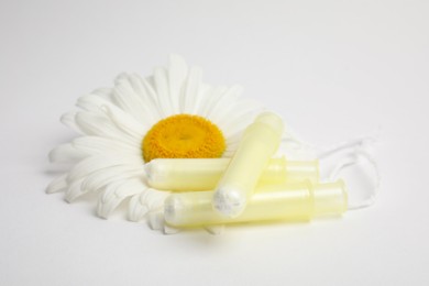 Photo of Applicator tampons and chamomile flower on white background. Menstrual hygiene product