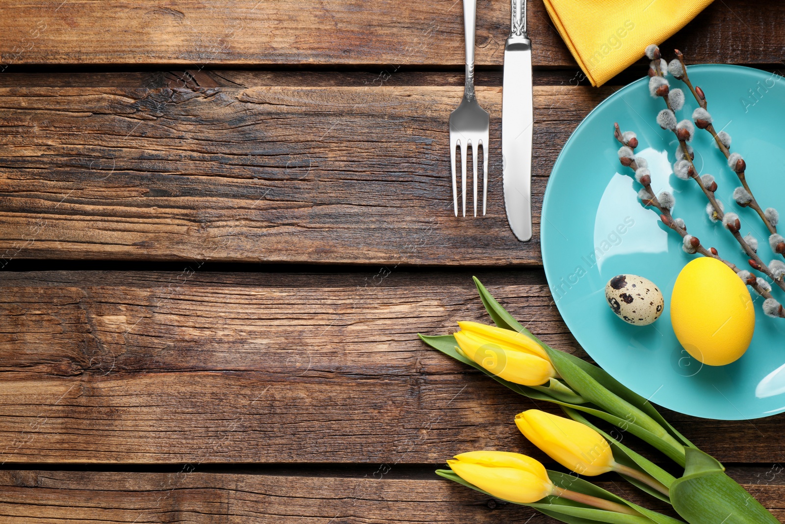 Photo of Festive Easter table setting with beautiful tulips and willow branches, flat lay. Space for text