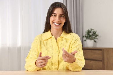 Photo of Happy woman sitting at table in room