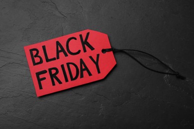 Red tag with words Black Friday on dark stone background, top view