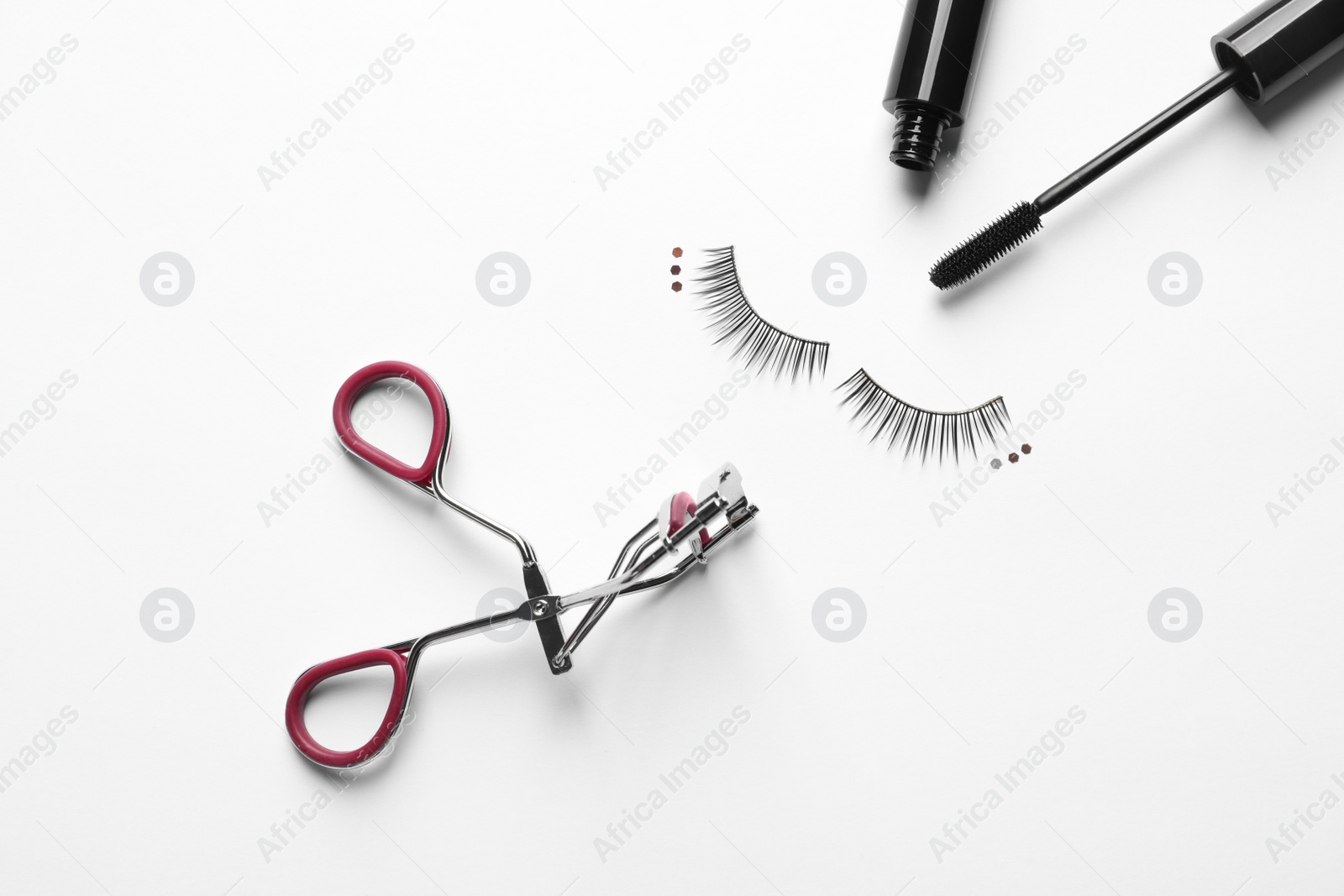 Photo of False eyelashes, mascara and curler on white background, top view