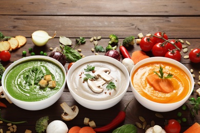 Various cream soups and ingredients on wooden background. Healthy food