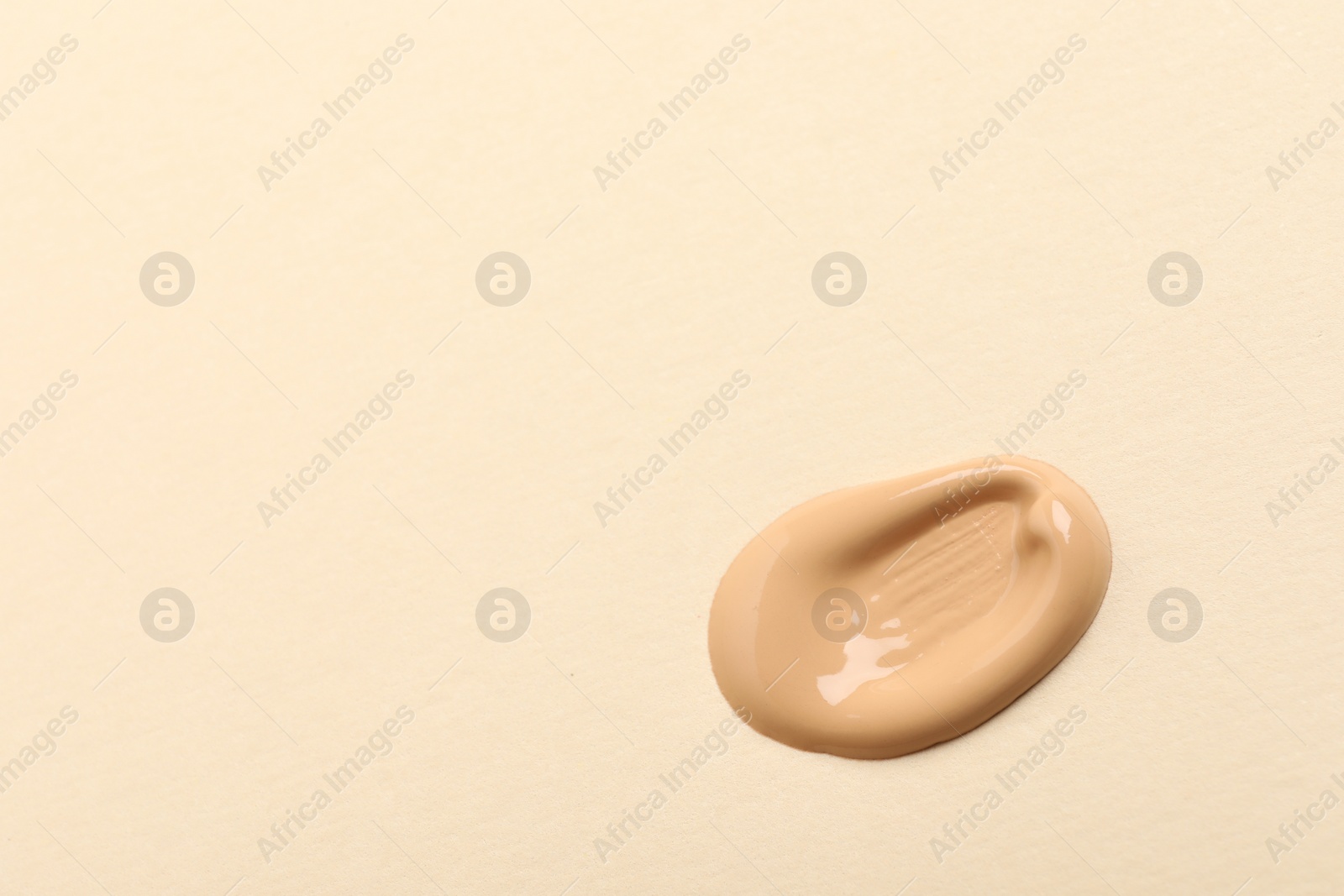 Photo of Sample of skin foundation on beige background, top view. Space for text