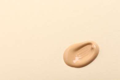 Photo of Sample of skin foundation on beige background, top view. Space for text