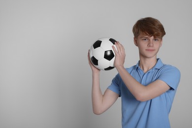 Photo of Teenage boy with soccer ball on light grey background. Space for text